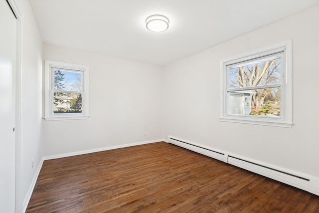 unfurnished room with dark hardwood / wood-style floors, a wealth of natural light, and a baseboard radiator