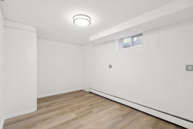 basement with light hardwood / wood-style floors and a baseboard radiator