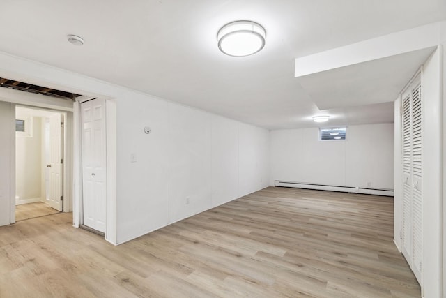 basement featuring light hardwood / wood-style floors and a baseboard heating unit