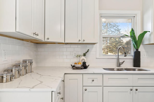 kitchen featuring white cabinetry, sink, and tasteful backsplash