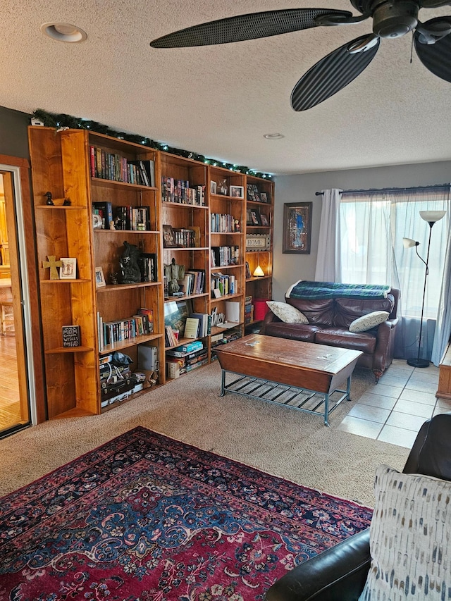 living room with a textured ceiling, ceiling fan, and light carpet