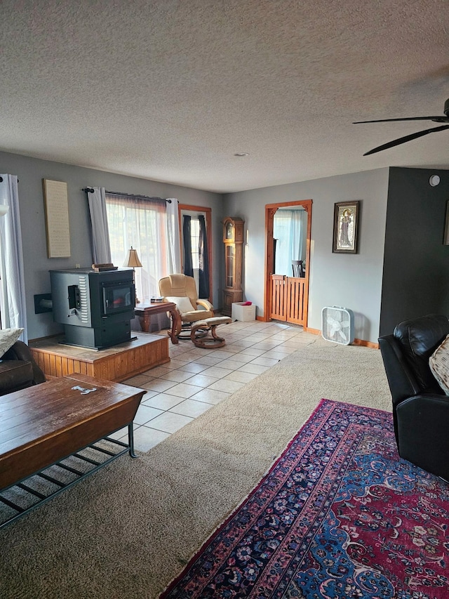 tiled living room with a wood stove, ceiling fan, and a textured ceiling