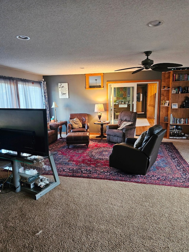 living room featuring carpet, ceiling fan, and a textured ceiling