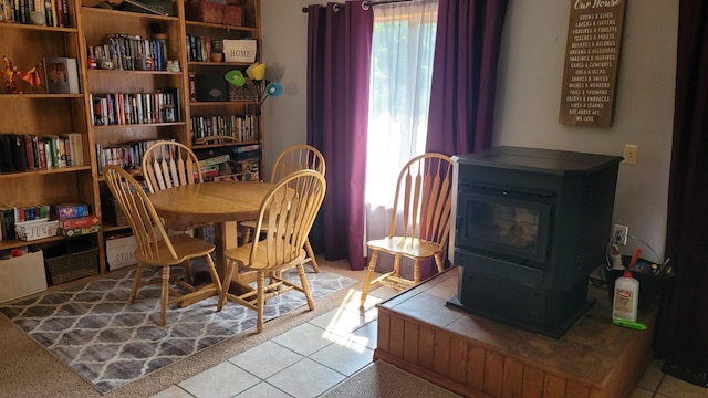 dining space with light tile patterned floors and a wood stove