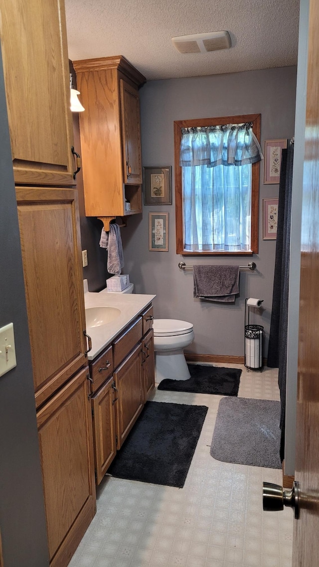 bathroom with vanity, a textured ceiling, and toilet