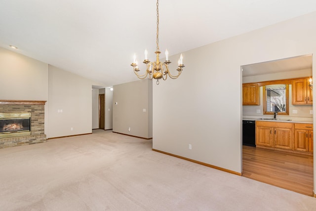 unfurnished living room with a notable chandelier, light wood-type flooring, sink, and a brick fireplace