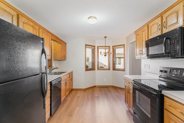 kitchen with sink, an inviting chandelier, light hardwood / wood-style floors, pendant lighting, and black appliances