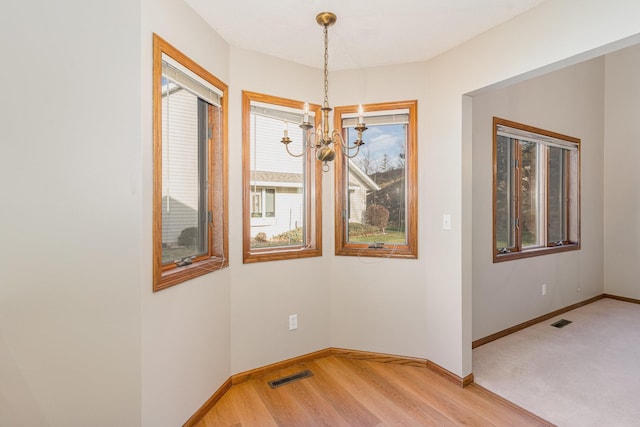 empty room with a chandelier and light hardwood / wood-style floors