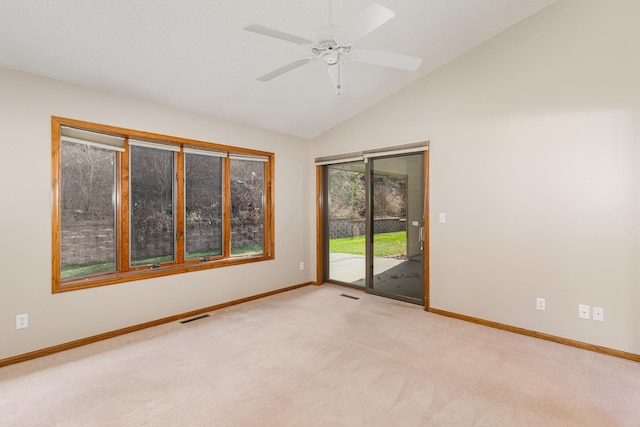 spare room featuring ceiling fan, light colored carpet, and vaulted ceiling