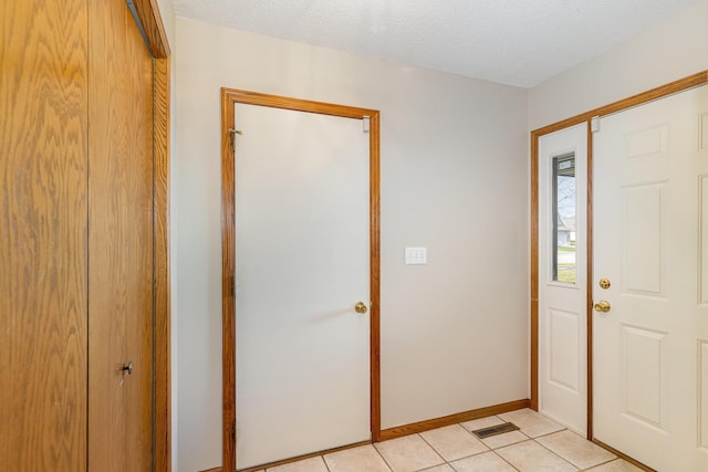 foyer featuring light tile patterned floors and a textured ceiling