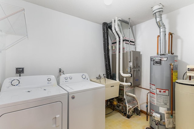 laundry area with a textured ceiling, washing machine and dryer, gas water heater, and sink