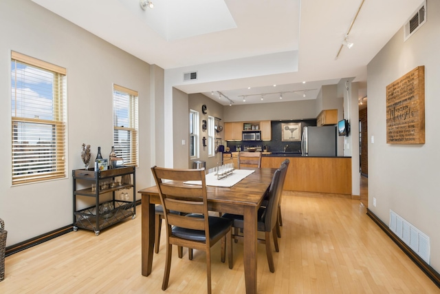 dining area featuring rail lighting and light hardwood / wood-style floors