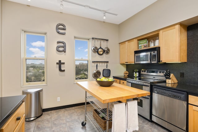 kitchen featuring decorative backsplash, track lighting, stainless steel appliances, light brown cabinets, and light tile patterned floors