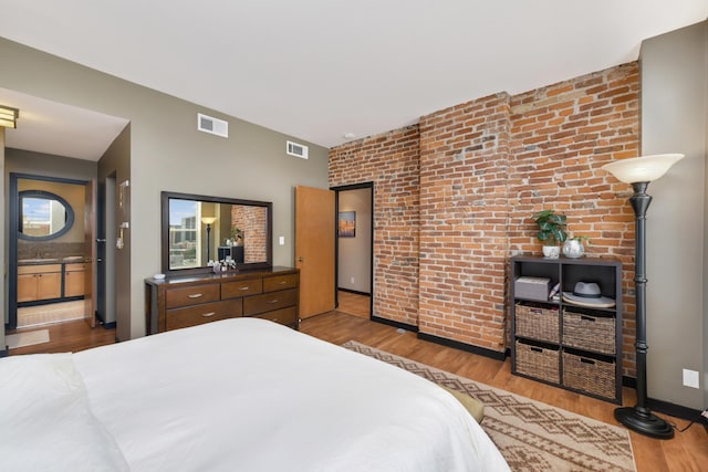 bedroom with brick wall and light wood-type flooring