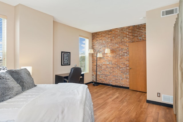 bedroom with brick wall and light wood-type flooring