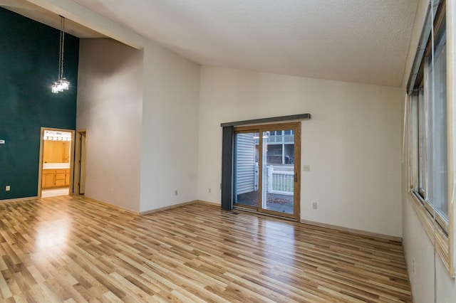 unfurnished room featuring a chandelier, a textured ceiling, high vaulted ceiling, and light hardwood / wood-style flooring