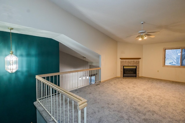 unfurnished living room featuring carpet, ceiling fan, vaulted ceiling, and a tiled fireplace