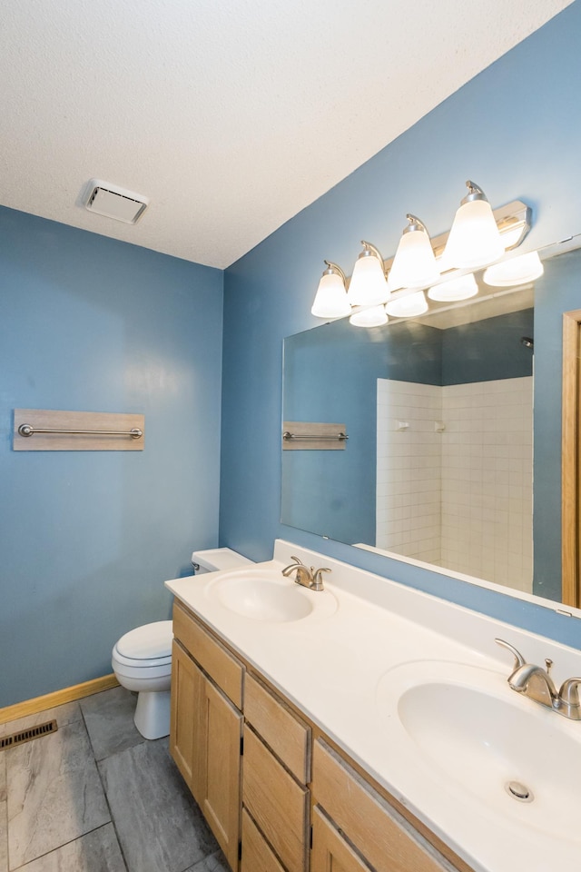 bathroom with toilet, a shower, and vanity