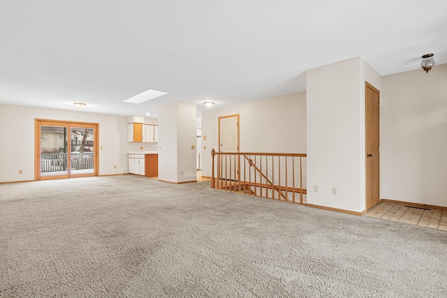 unfurnished living room with light carpet and a skylight