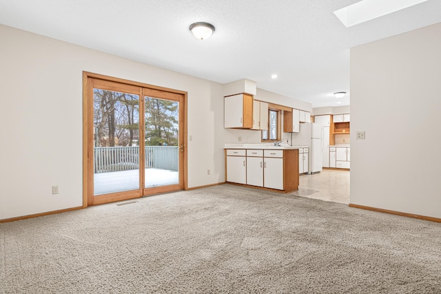 unfurnished living room featuring separate washer and dryer, a skylight, light colored carpet, and sink