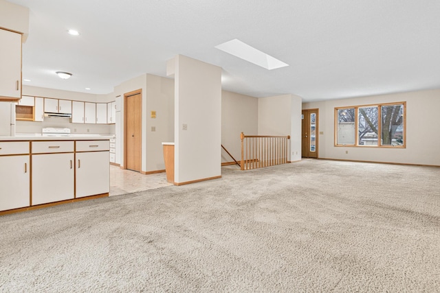 unfurnished living room featuring a skylight and light colored carpet