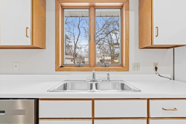 kitchen featuring stainless steel dishwasher, white cabinetry, and sink