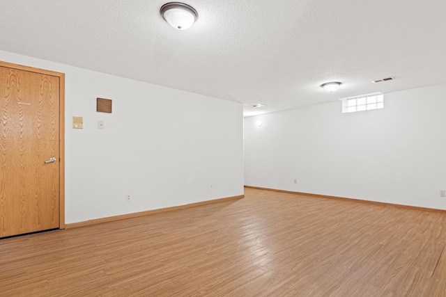 unfurnished room with a textured ceiling and light wood-type flooring