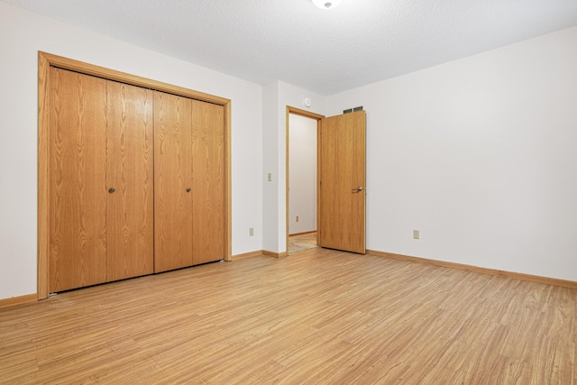 unfurnished bedroom with a textured ceiling, light wood-type flooring, and a closet