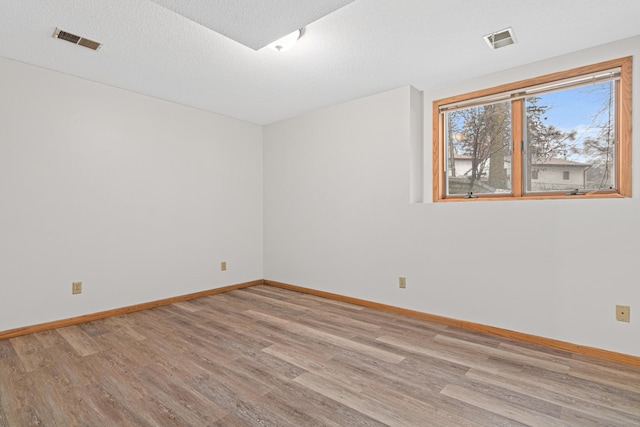 unfurnished room with a textured ceiling and light hardwood / wood-style flooring