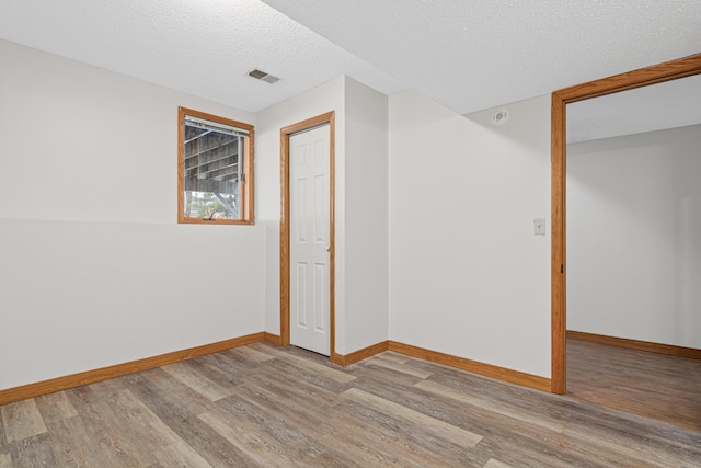 unfurnished bedroom with a textured ceiling, light hardwood / wood-style floors, and a closet