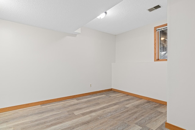 spare room with a textured ceiling and light hardwood / wood-style flooring