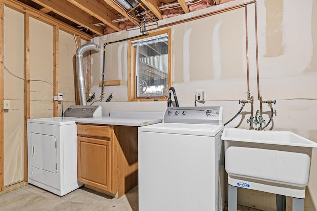 clothes washing area with cabinets and washing machine and clothes dryer