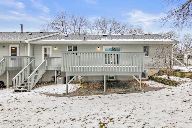 snow covered property with central AC unit and a deck