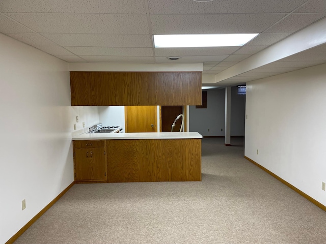 kitchen with kitchen peninsula, a paneled ceiling, and light colored carpet