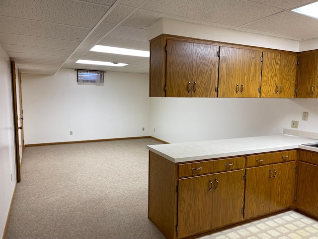 kitchen featuring a drop ceiling and light carpet