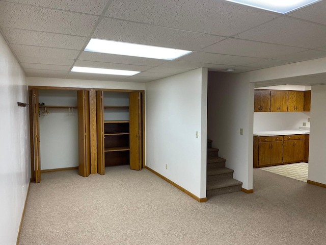 basement featuring a drop ceiling and light carpet