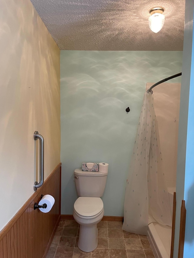 bathroom with toilet, a textured ceiling, and a shower with shower curtain