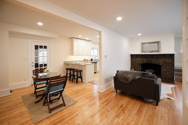 living room featuring a fireplace, light hardwood / wood-style floors, and sink