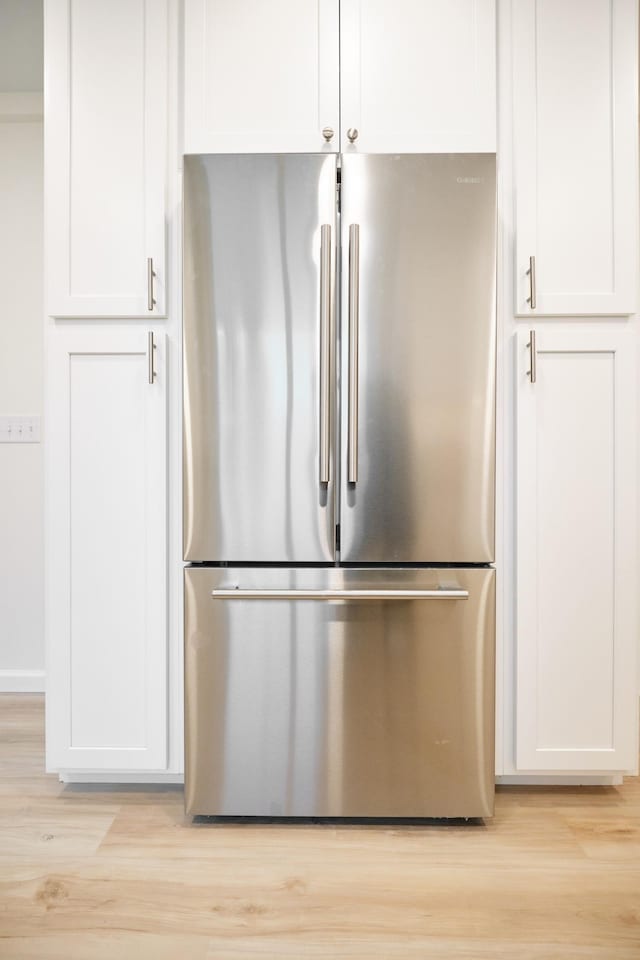 interior details with light wood-type flooring, white cabinetry, and stainless steel refrigerator