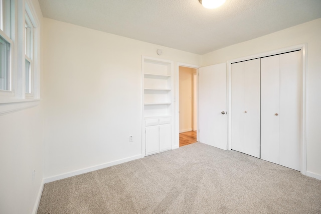 unfurnished bedroom featuring a closet, light colored carpet, and a textured ceiling