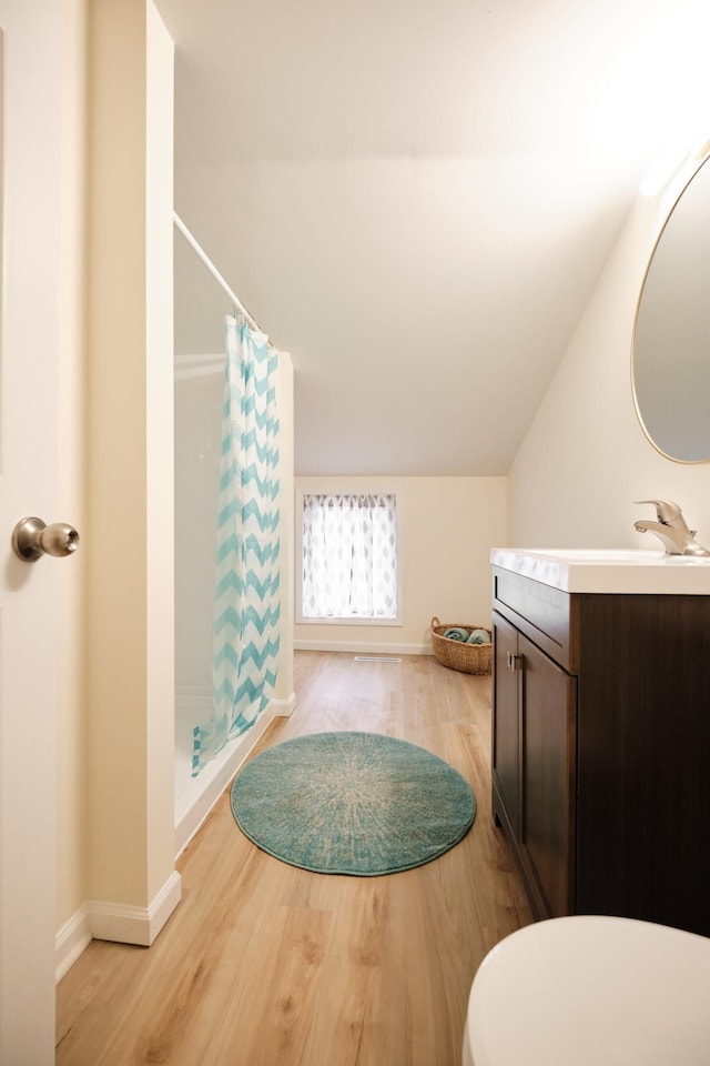 bathroom featuring curtained shower, vanity, wood-type flooring, and vaulted ceiling