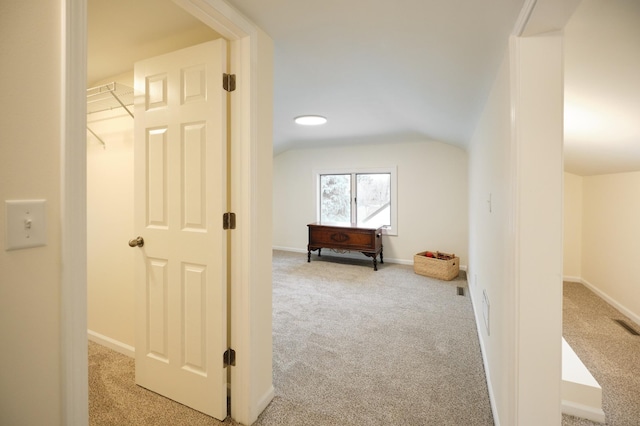 hall with light colored carpet and vaulted ceiling