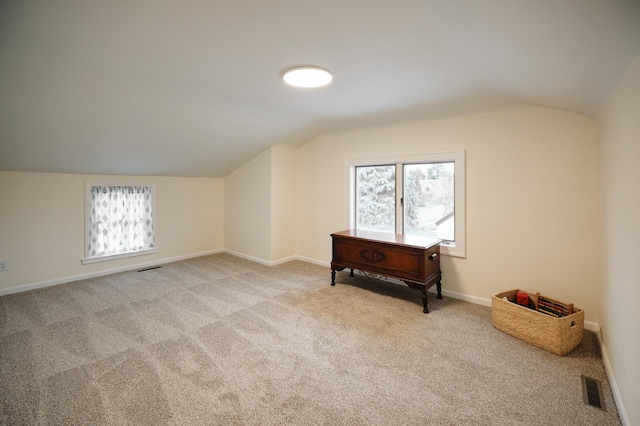 bonus room with light colored carpet and lofted ceiling