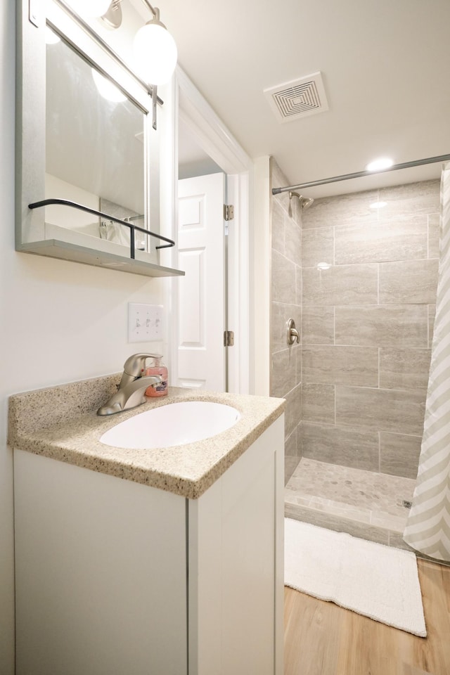 bathroom featuring hardwood / wood-style floors, vanity, and tiled shower