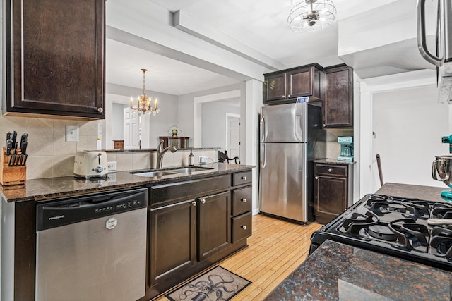 kitchen featuring sink, light hardwood / wood-style flooring, dark brown cabinets, dark stone countertops, and stainless steel appliances