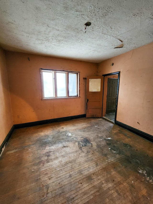 unfurnished room with dark hardwood / wood-style flooring and a textured ceiling