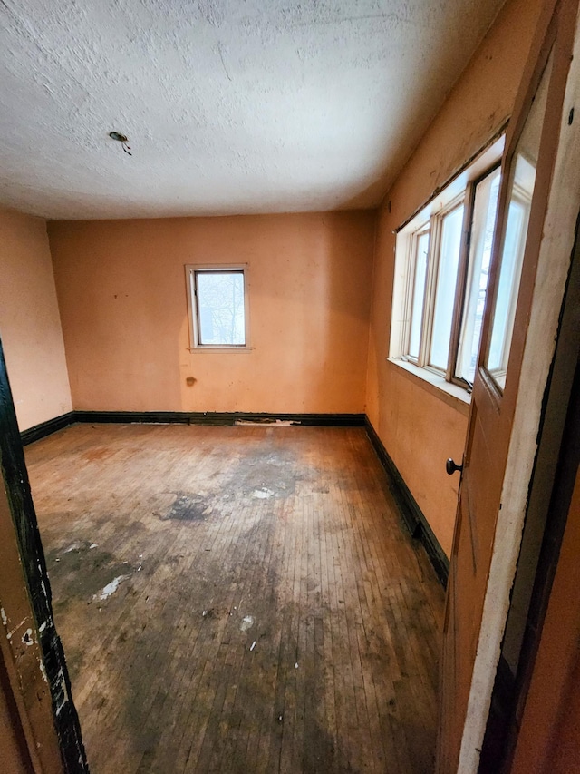 unfurnished room with a textured ceiling and hardwood / wood-style flooring