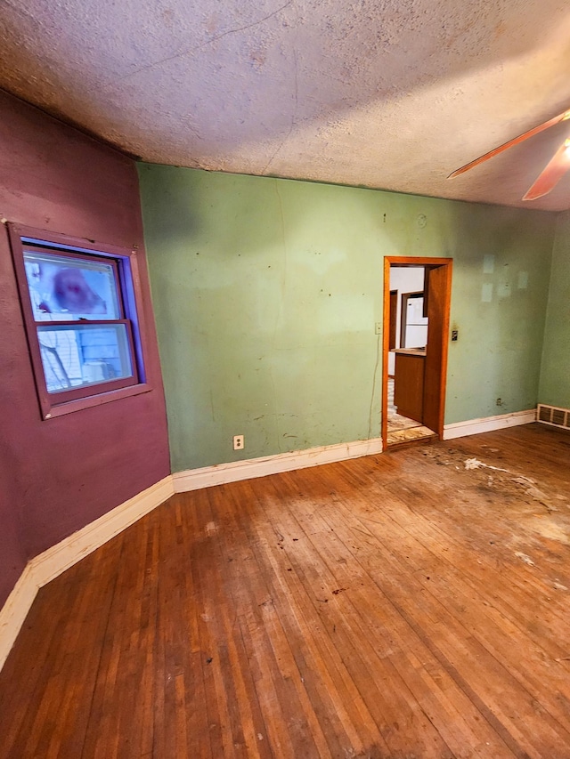 spare room with hardwood / wood-style flooring, ceiling fan, and a textured ceiling