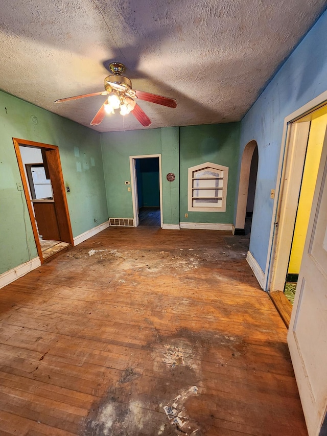 unfurnished bedroom with hardwood / wood-style flooring, ceiling fan, white fridge, and a textured ceiling