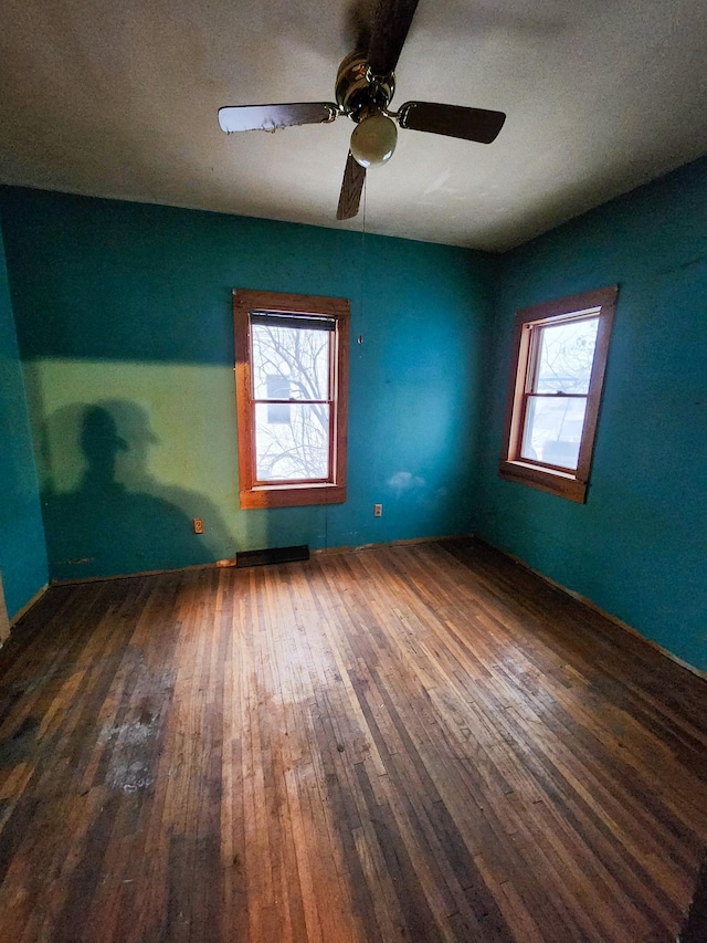 empty room with dark hardwood / wood-style floors, ceiling fan, and a wealth of natural light